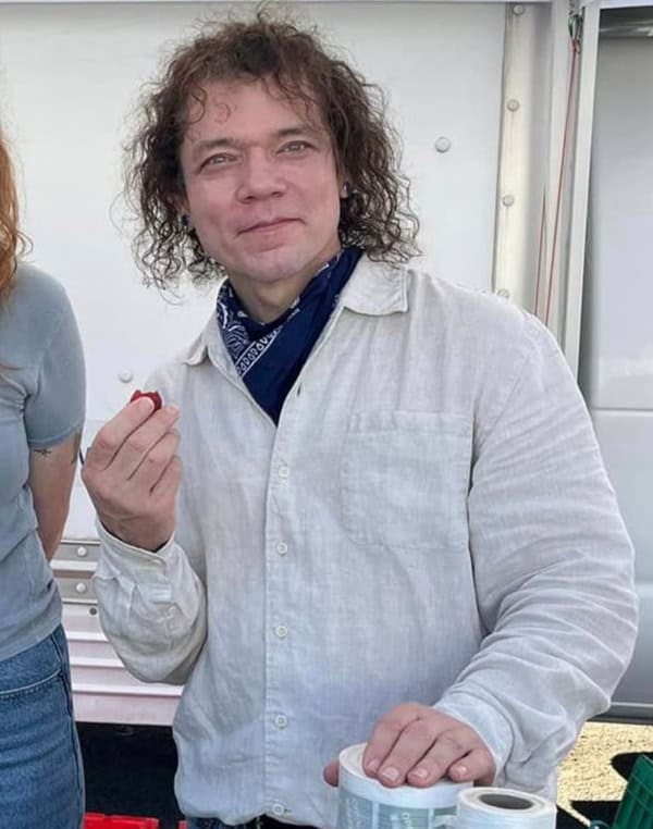 Friday wearing light linen shirt and blue bandana while eating a strawberry