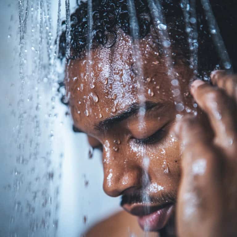 Black man surrounded by water droplets taking hot shower